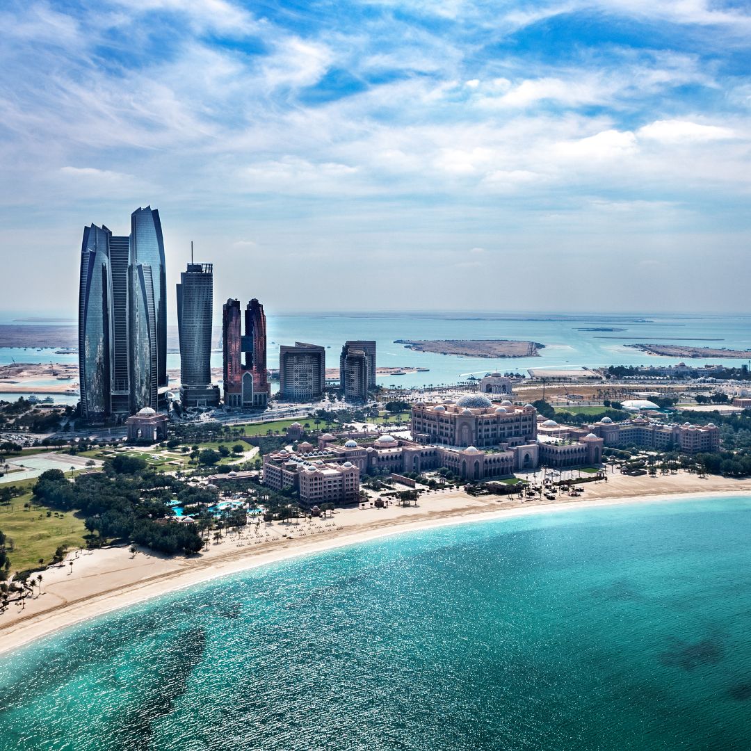 The Abu Dhabi skyline along the Corniche at dusk, with the towers of the central business district rising beside the Gulf, the United Arab Emirates capital and a leading sovereign-wealth and energy hub for private jet charter.